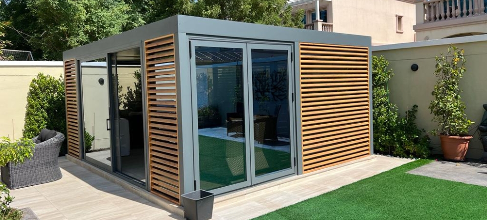 A bespoke timber-framed garden room with glass walls set in a lush Dubai backyard by Deco Wood.